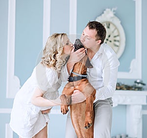 Portrait of a young married couple kissing their pet