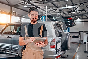 Portrait of young mechanic holding digital tablet in his auto repair shop