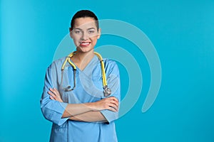 Portrait of young medical assistant with stethoscope on color background