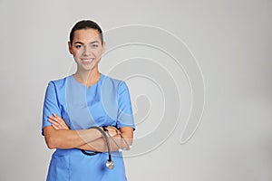 Portrait of young medical assistant with stethoscope on color background