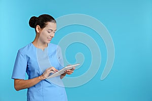 Portrait of young medical assistant with tablet on color background