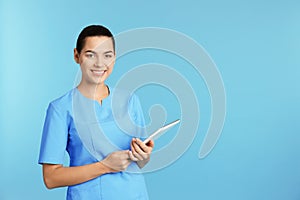 Portrait of young medical assistant with tablet on color background. photo