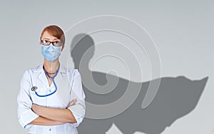 Portrait of young medical doctor with super hero woman cape behind her shoulder