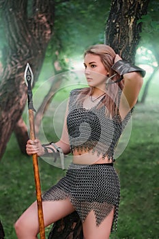 Portrait of a young medieval woman warrior, dressed in chain mail armor with a spear in her hands