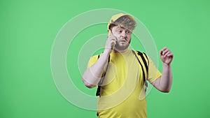 Portrait of young men talking for phone, specifying delivery address. Redhead male in yellow delivery courier uniform