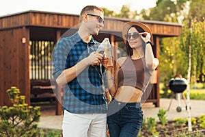 Young man and woman with drinks walking in a city park, on a summer sunny day, young people walking outdoors