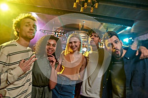 Portrait of young men and women looking at camera and smiling. Multiracial group of friends hanging out at party in the