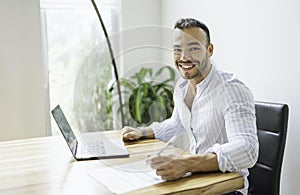 Portrait young mexican attractive businessman working at modern home office with computer laptop