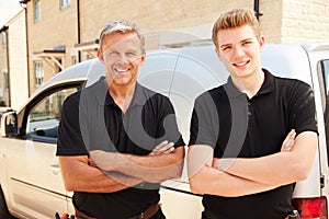 Portrait of a young and a middle aged tradesman by their van