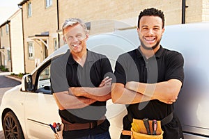 Portrait of a young and a middle aged tradesman by their van