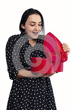 Portrait of young middle-eastern woman surprised with gift box. Female unpacking romantic present box from her lover