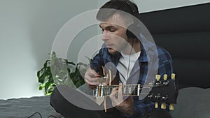 Portrait of young millennial playing on electric guitar.   Guitar player performs lyric music. Man in headphones plays on guitar.