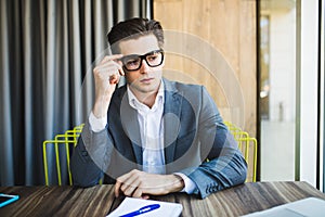 Portrait of young minded man thinking about task in office