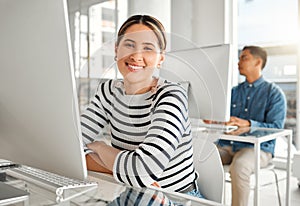 Portrait of a young mixed race businesswoman using a desktop computer in an office at work. Happy hispanic female