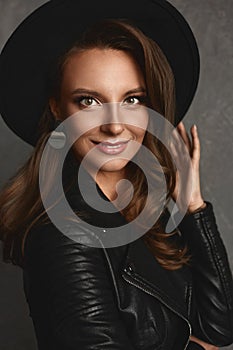 Portrait of young model woman with bright makeup and perfect skin in a black trendy hat and leather jacket