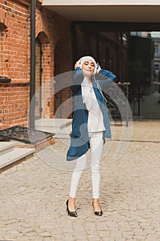 Portrait of young modern arabian woman holding mobile phone and listening the music to headphone.