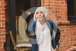 Portrait of young modern arabian woman holding mobile phone and listening the music to headphone.