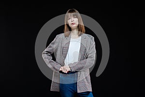 Portrait of a young modern business woman in a jacket on a black isolated background.