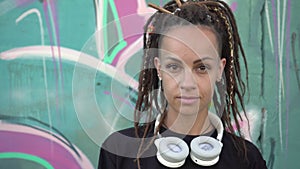 Portrait of young modern woman against graffiti background. Modern urban youth. Attractive hipster woman with dreadlocks