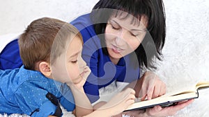 Portrait of a young mother and child. Family concept. Mom reads a book to her son in the nursery.