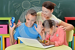 Portrait of young mother with children playing computer game with laptop