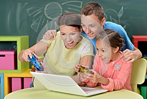 Portrait of young mother with children playing computer game wit