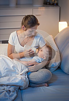 Portrait of young mother giving bottle with milk to her baby in