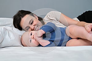 Portrait of young mother and her baby son, parent and baby lying in bed together