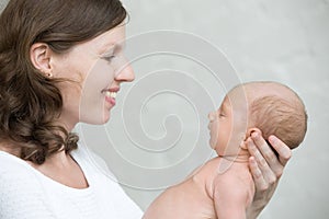 Portrait of young mother and her newborn baby. Side view