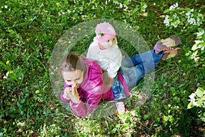 Portrait of young mother and her small daughter in the park full of apple blossom trees in a spring day. Woman and girl in nature