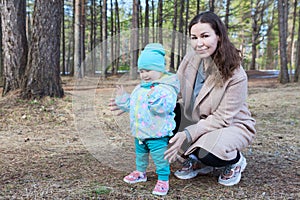 Portrait of young mother with her toddler son walking in spring forest