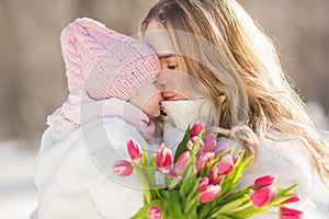 Portrait of young mother kisses her little baby in the winter