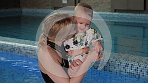 Portrait of a young mother with a small baby in the pool.