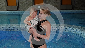 Portrait of a young mother with a small baby in the pool.