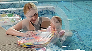 Portrait of a young mother with a small baby in the pool.