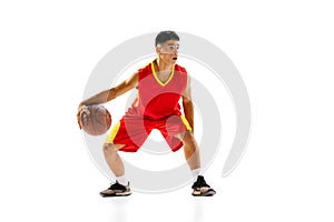 Portrait of young motivated man, basketball player training, dribbling isolated over white studio background