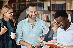 Portrait of young multicultural friends reading books together in the library