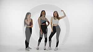 Portrait of young multiethnic models isolated white studio background. Group of three positive multiracial girls posing