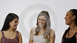 Portrait of young multiethnic models on white studio background close up. Group of three appealing multiracial girls