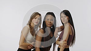 Portrait of young multiethnic models on white studio background close up. Group of three appealing multiracial girls