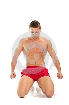 Portrait of young muscular man on his knees stretching