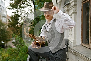 Portrait of young musician holding saxophone musical instrument