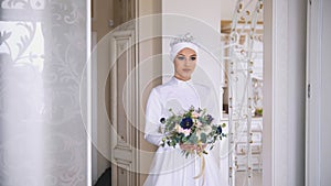 Portrait of young muslim bride with professional make up in white dress with flowers