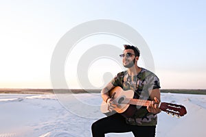 Portrait of young Muslim man who plays music on guitar among san