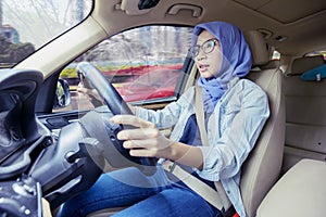 Portrait of young muslim woman driving car