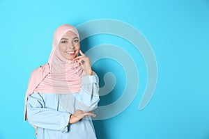 Portrait of young Muslim woman in hijab against color background. photo