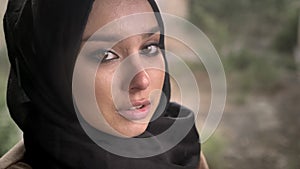 Portrait of young muslim woman in hijab looking at camera with sad depressed expression during rain