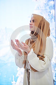Portrait of young muslim woman praying or making dua to God