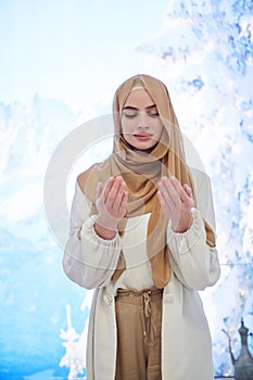 Portrait of young muslim woman praying or making dua to God