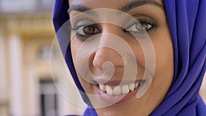 Portrait of young muslim woman smiling at camera during rain, beautiful female with pierced nose